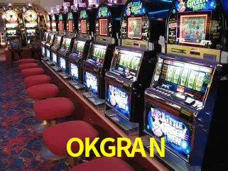 Escena dinámica inspirada en casino con iluminación OKGRAN, cartas, fichas e íconos de juegos digitales en un espacio moderno de juegos.